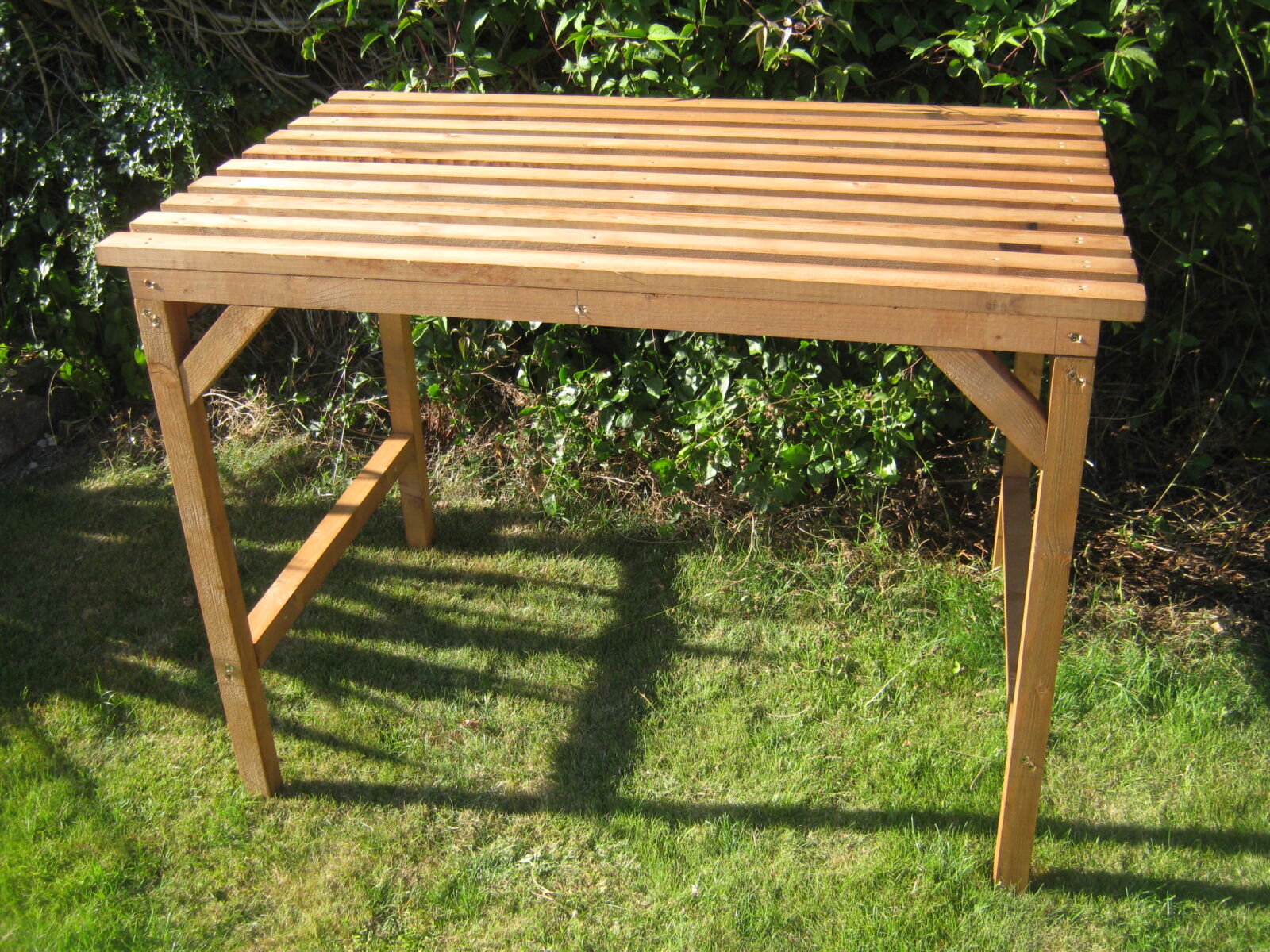 Wooden greenhouse staging table on a sunlit garden lawn - Greenhouse Staging
